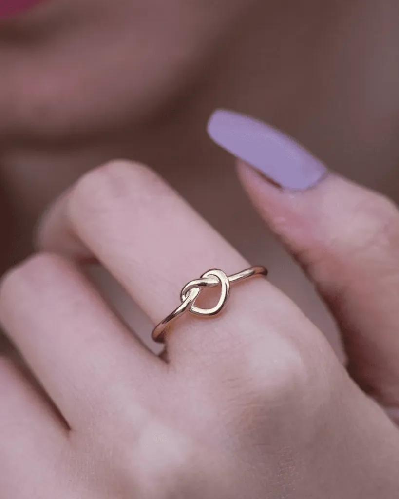 Fine gold-tone band tied into a single love knot that sits slightly proud of the ring