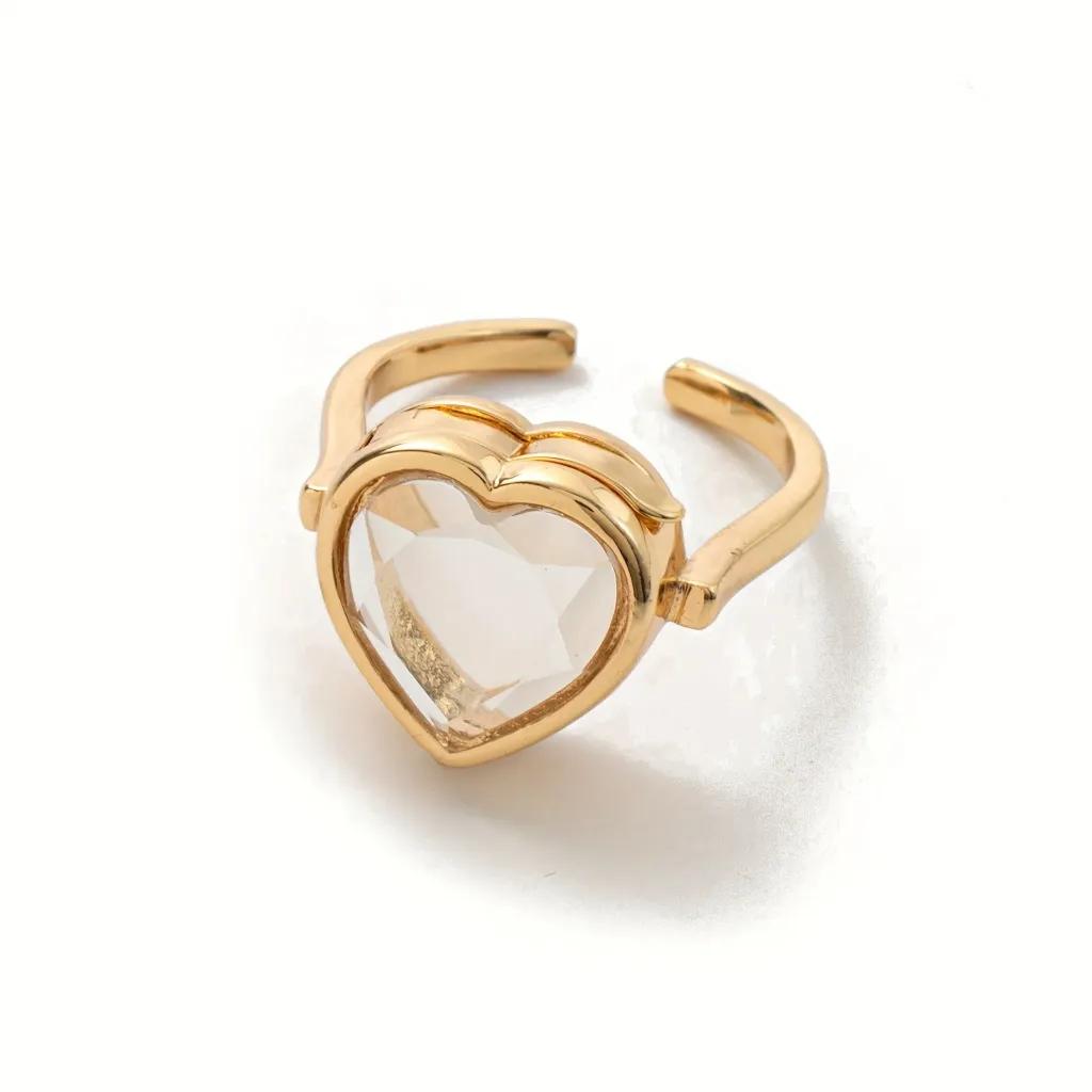 Large faceted clear crystal heart in a scalloped gold-plated setting on an open ring