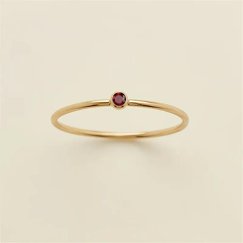 Hair-fine gold-plated band with one small red cubic zirconia sunk into a bezel