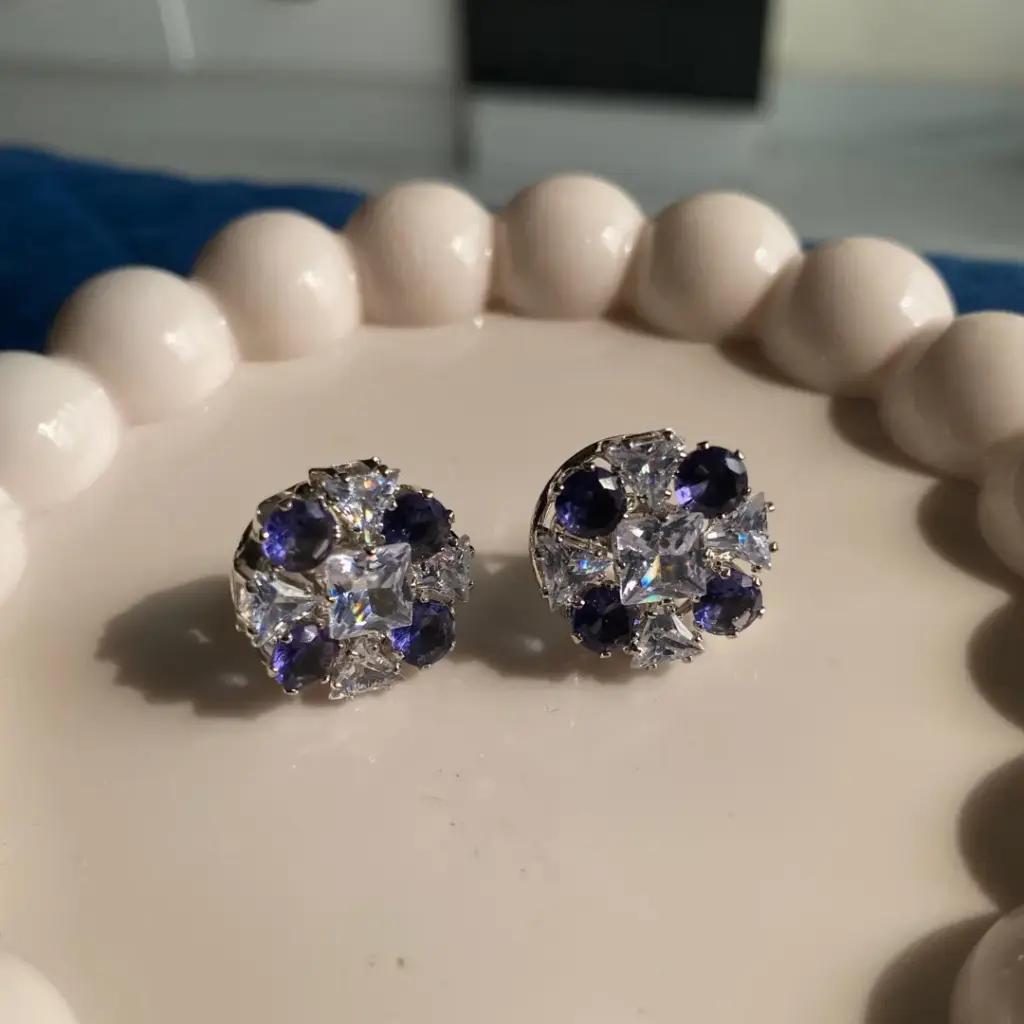 Deep blue cubic zirconia rounds circling a square princess-cut centre on a silver-plated stud