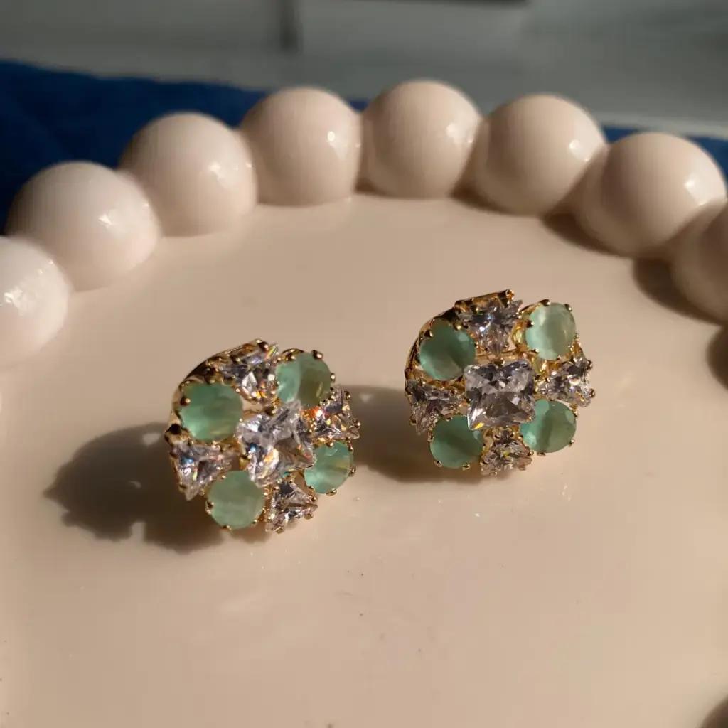 Frosted mint green stones alternating with clear trillion cuts around a square gold-plated centre
