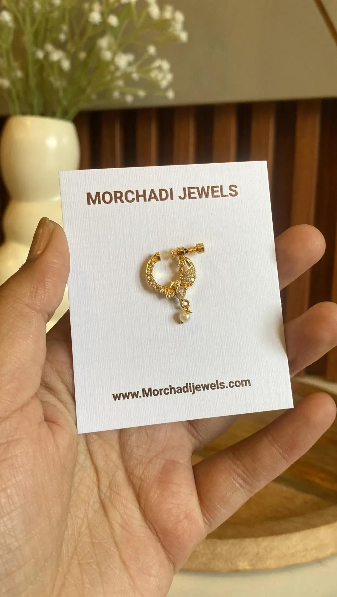 Peacock outlined in clear cubic zirconia along a gold-plated nose ring with a pearl-look bead
