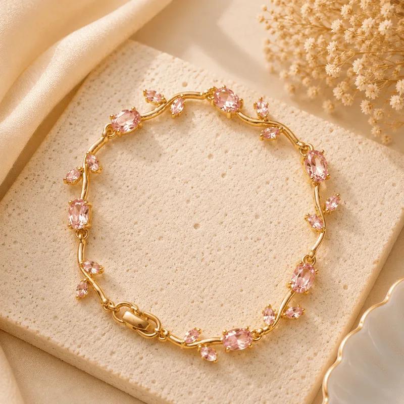 Alternating pink oval and marquise cubic zirconia along a waved gold-tone bracelet
