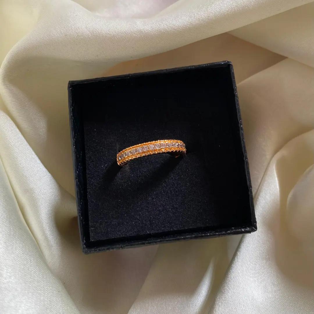 Slim channel-set cubic zirconia band ring with beaded milgrain edges in rose gold plating, shown in a black ring box
