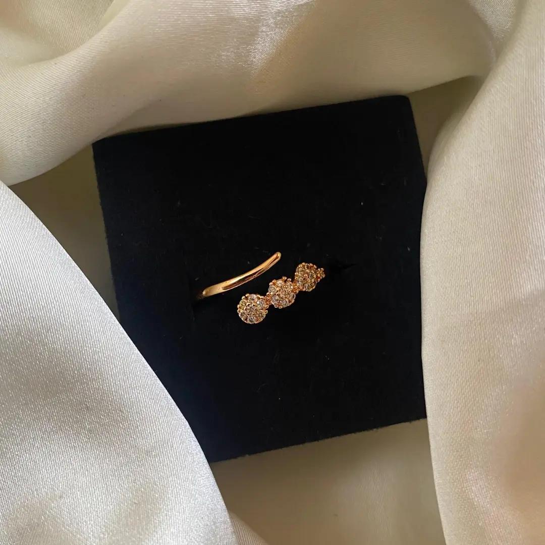 Rose gold-toned ring with cubic zirconia stones on an adjustable band