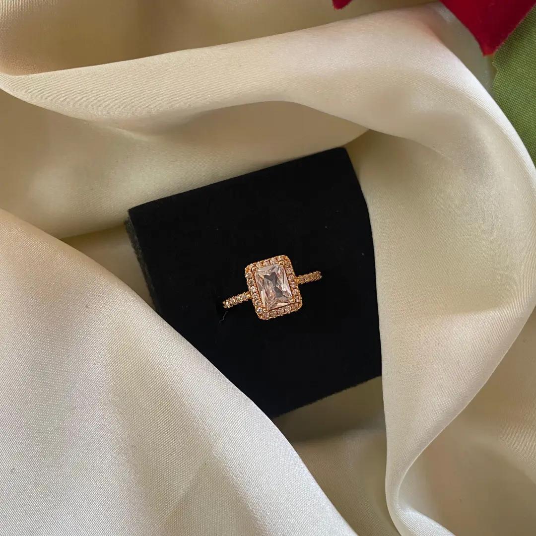Rose gold-plated ring with an emerald-cut cubic zirconia stone framed by a halo