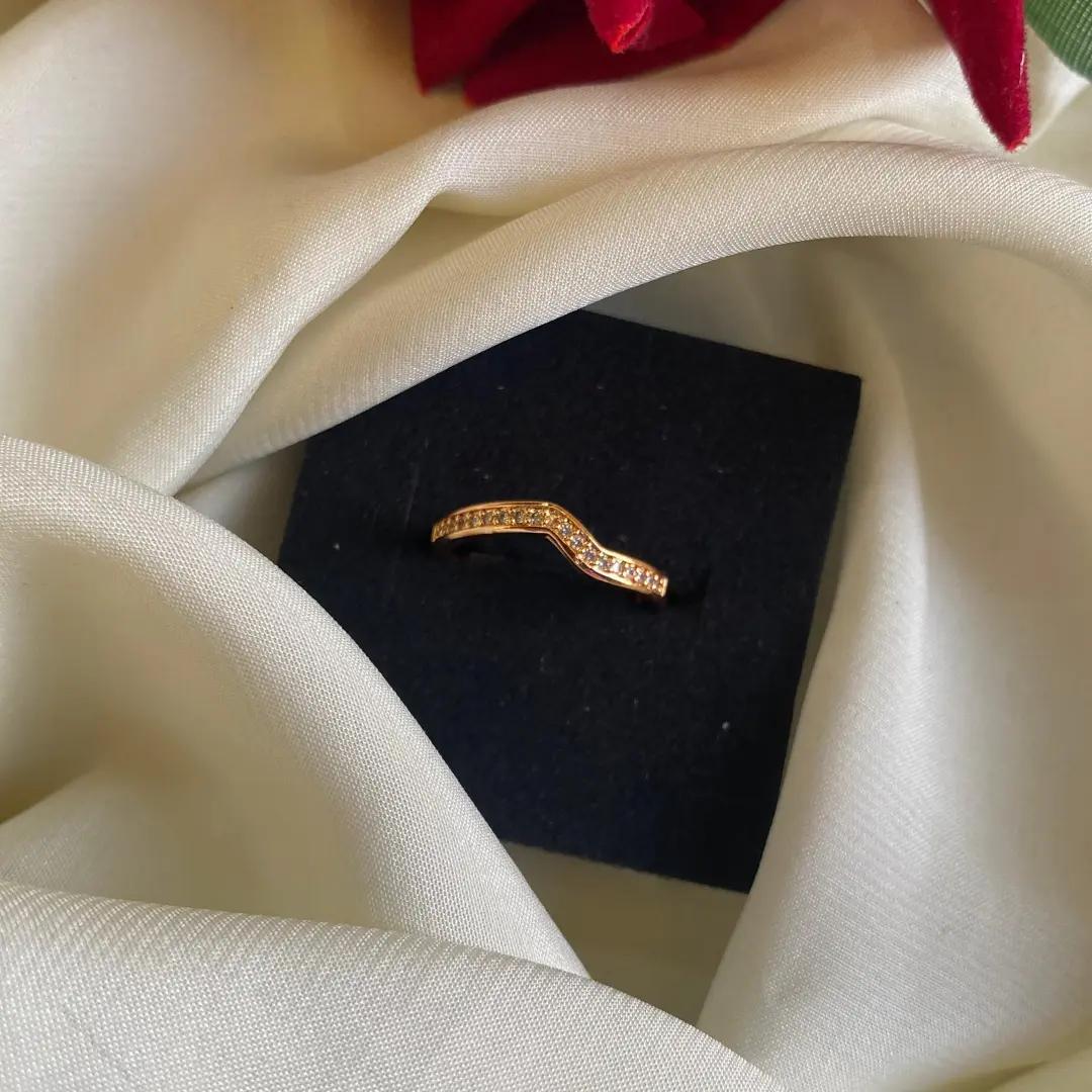 Rose gold-plated band ring with a V dip lined in small cubic zirconia stones, on a black display card