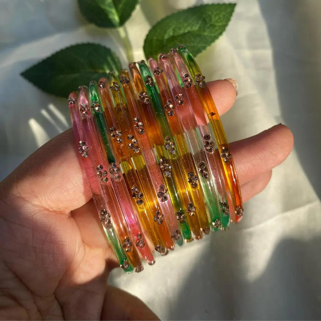 Multicolour glass bangles in pink, orange, yellow and green with scattered glitter flecks
