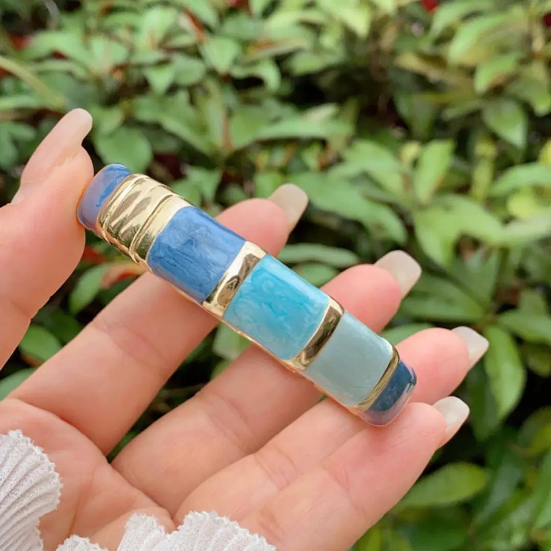 Blue ombre enamel kada with gold-plated segment dividers, shown resting in an open palm
