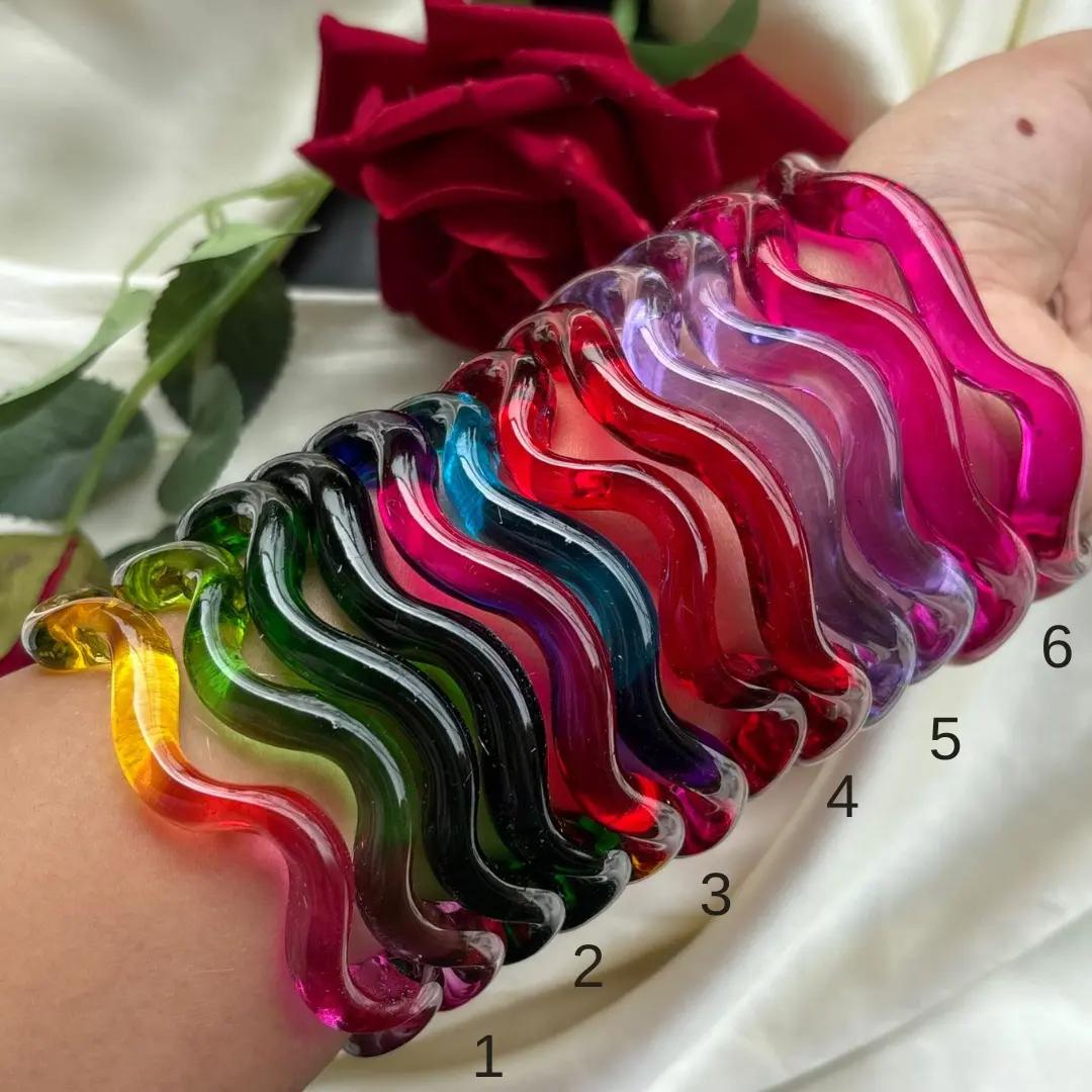 Deep-wave glass kangan in magenta, purple, red, black and ombre shades stacked on a wrist, numbered one to six