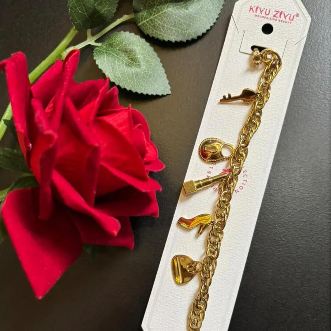 Gold-plated charm bracelet with key, lock, lipstick, shoe and heart charms on a curb-link chain