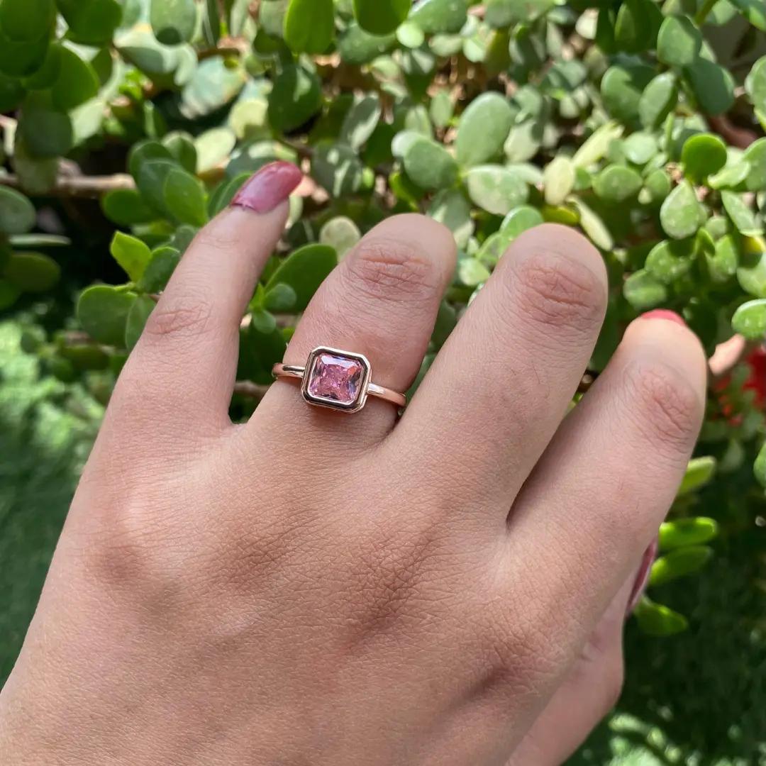 Gold-plated adjustable ring with a bezel-set square pink stone, worn on a finger