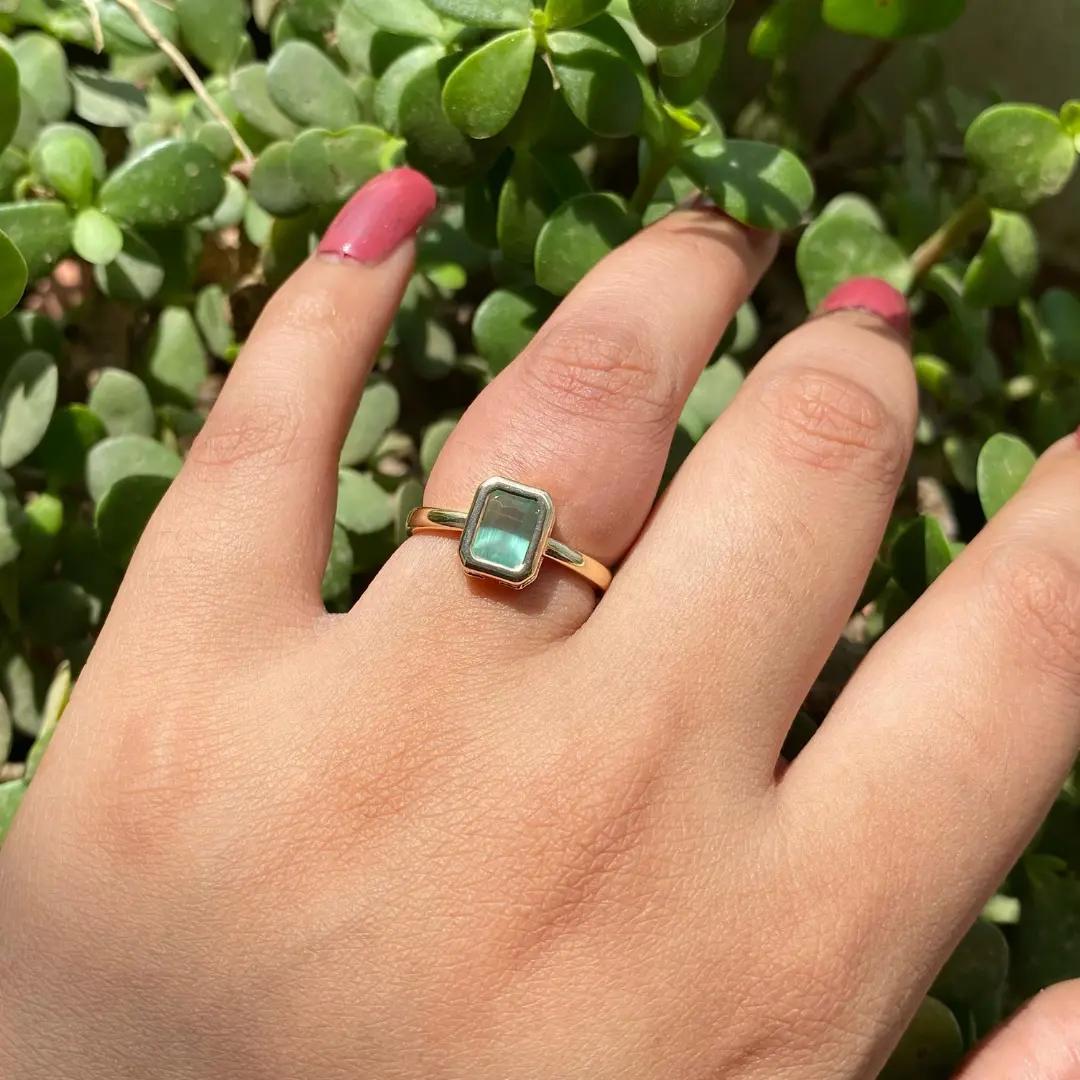 Gold-tone ring with a bezel-set rectangular green stone on a thin band