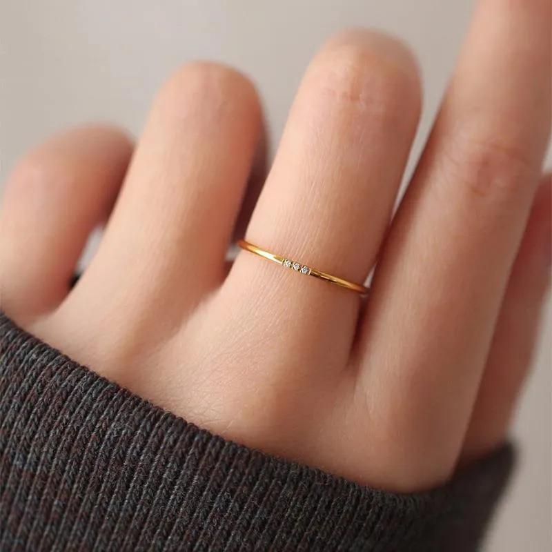 Thin gold-finish ring with three small clear stones set flush into the band