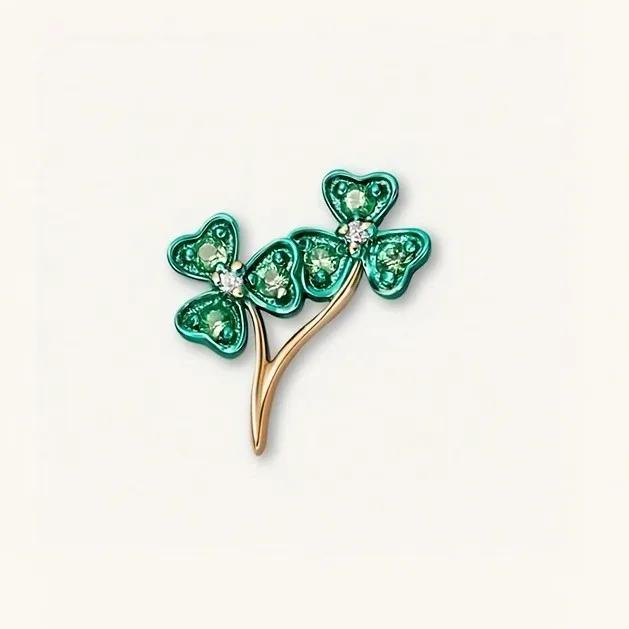 Charm of two green clover heads with tiny clear stone centres on a curved golden stem