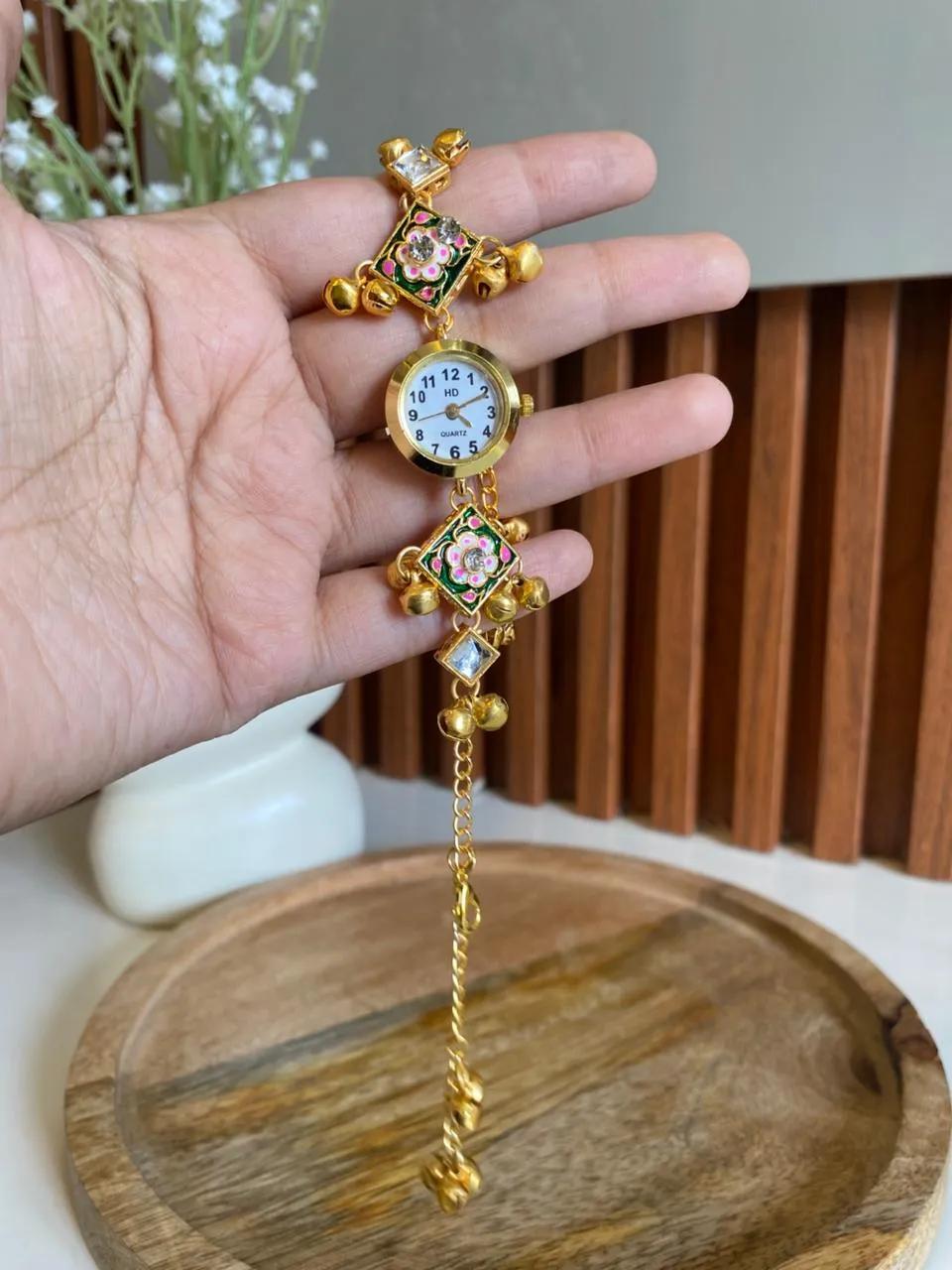 Gold-tone bracelet watch with green meenakari floral panels and small gold ghungroo bells