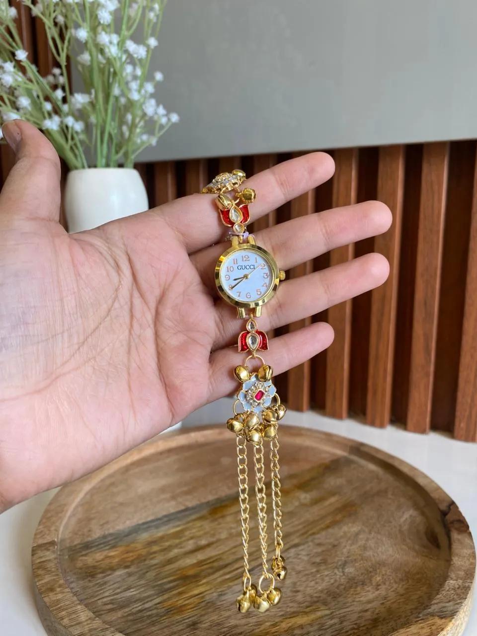 Gold-tone bracelet watch with red kundan charms and a grey floral kundan pendant