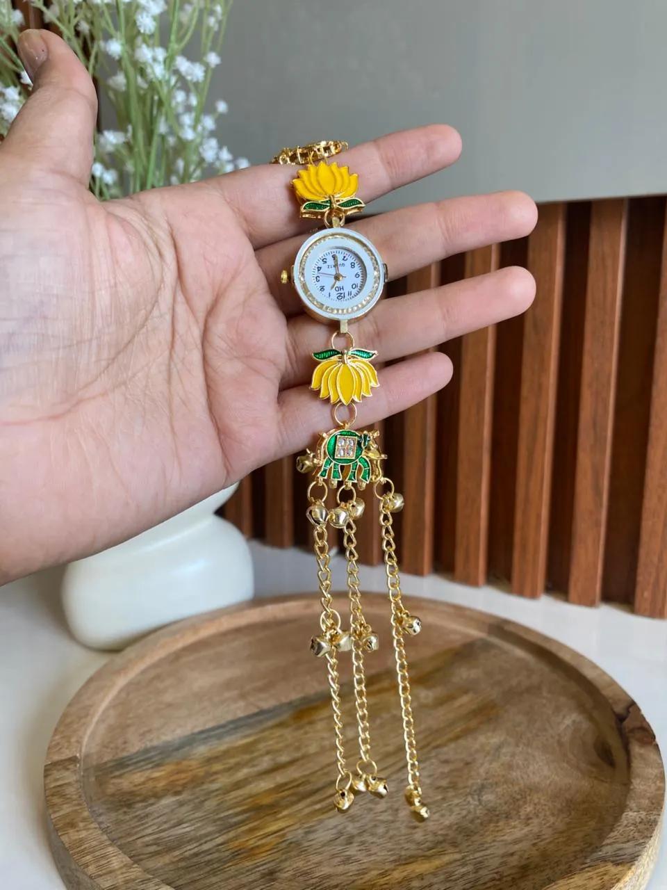 Gold-tone bracelet watch with yellow lotus charms and a green meenakari elephant pendant