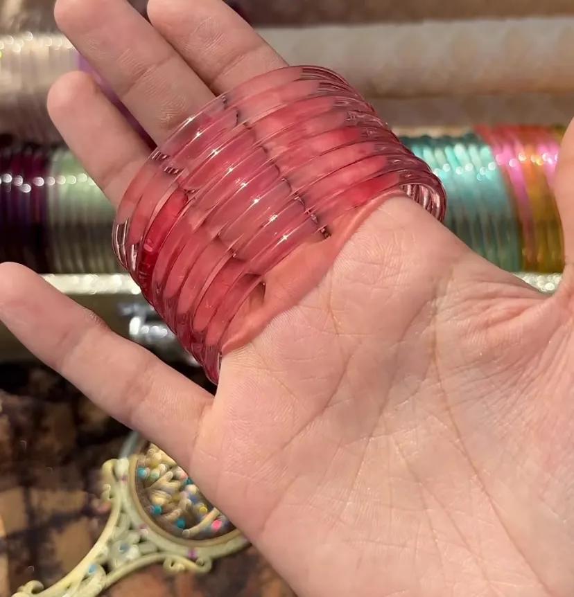 Stack of eight translucent blush pink glass bangles worn on a wrist