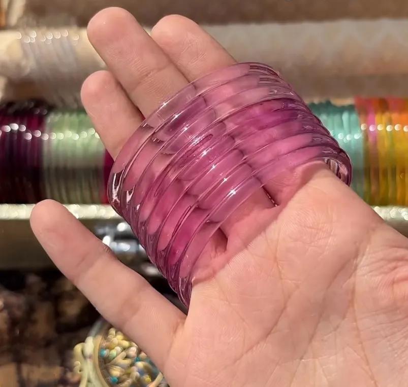 Stack of eight translucent rose pink glass bangles worn on a wrist