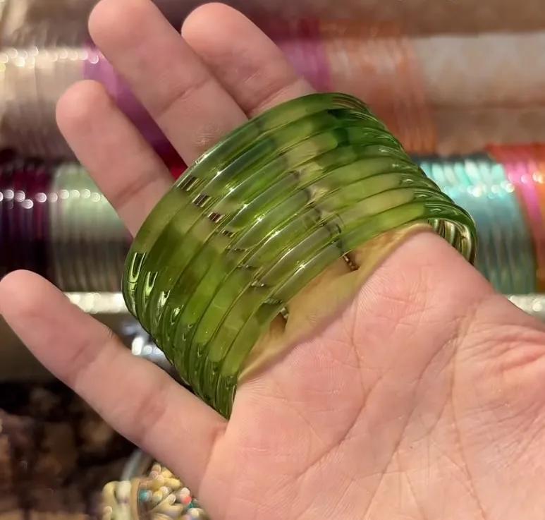 Stack of eight translucent pistachio green glass bangles worn on a wrist
