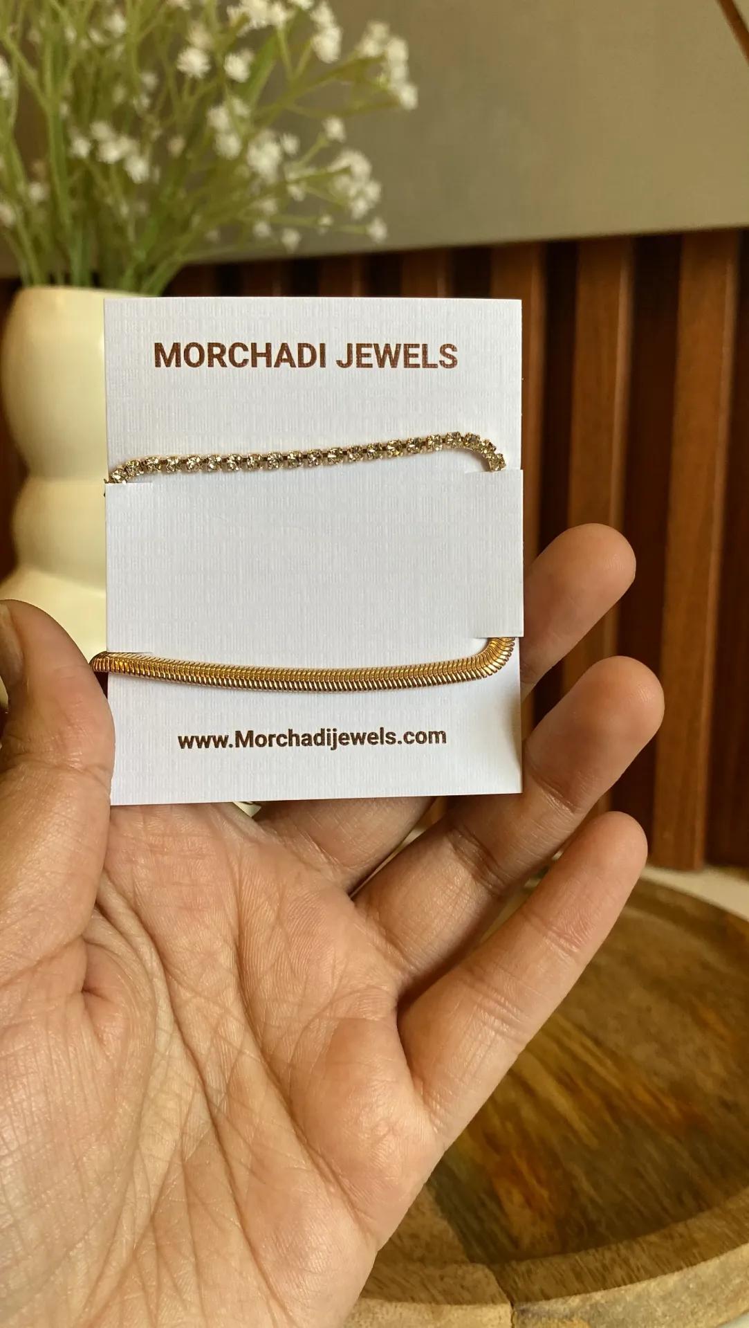 Gold-toned tennis bracelet with cubic zirconia stones paired with a flat snake chain bracelet