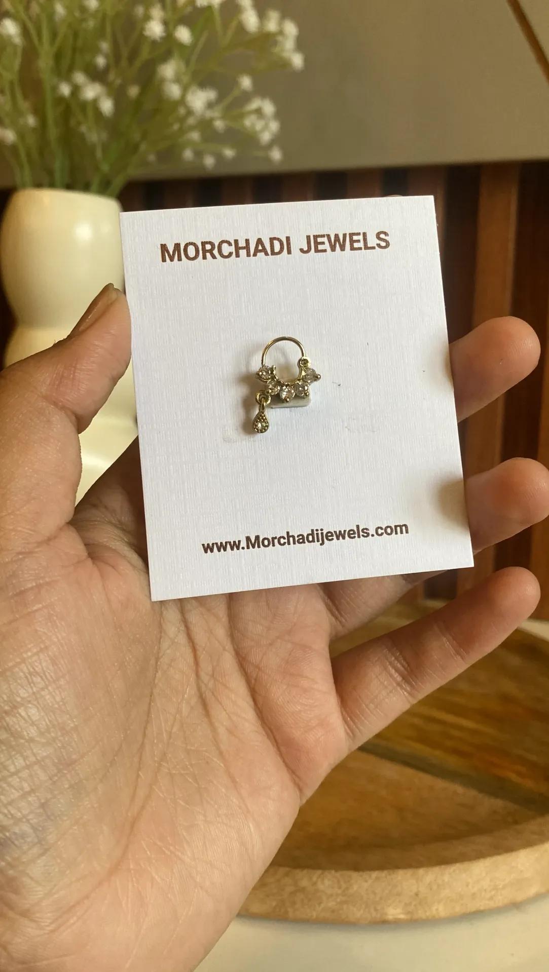 Gold-toned nath with a small cluster of clear stones and a teardrop drop charm
