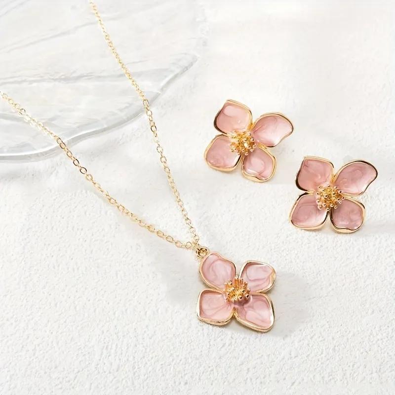 Gold-toned necklace and stud earrings with a soft pink enamel four-petal flower design
