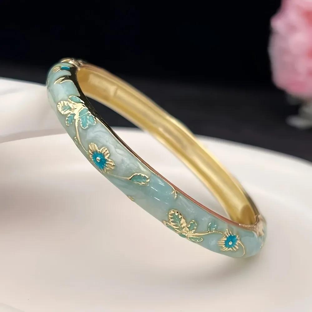 Pale aqua enamel kada with gold-toned botanical vine pattern and deep blue flower centres