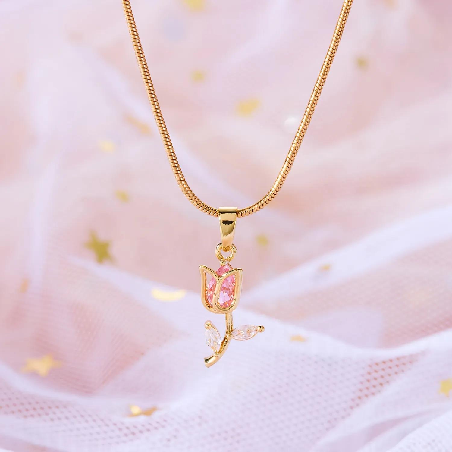 Gold-toned snake chain necklace with a pink tulip-shaped pendant and clear leaf stones