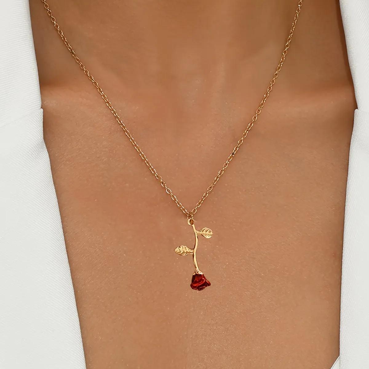 Gold-toned pendant necklace shaped like an upside-down rose stem with a crimson bud