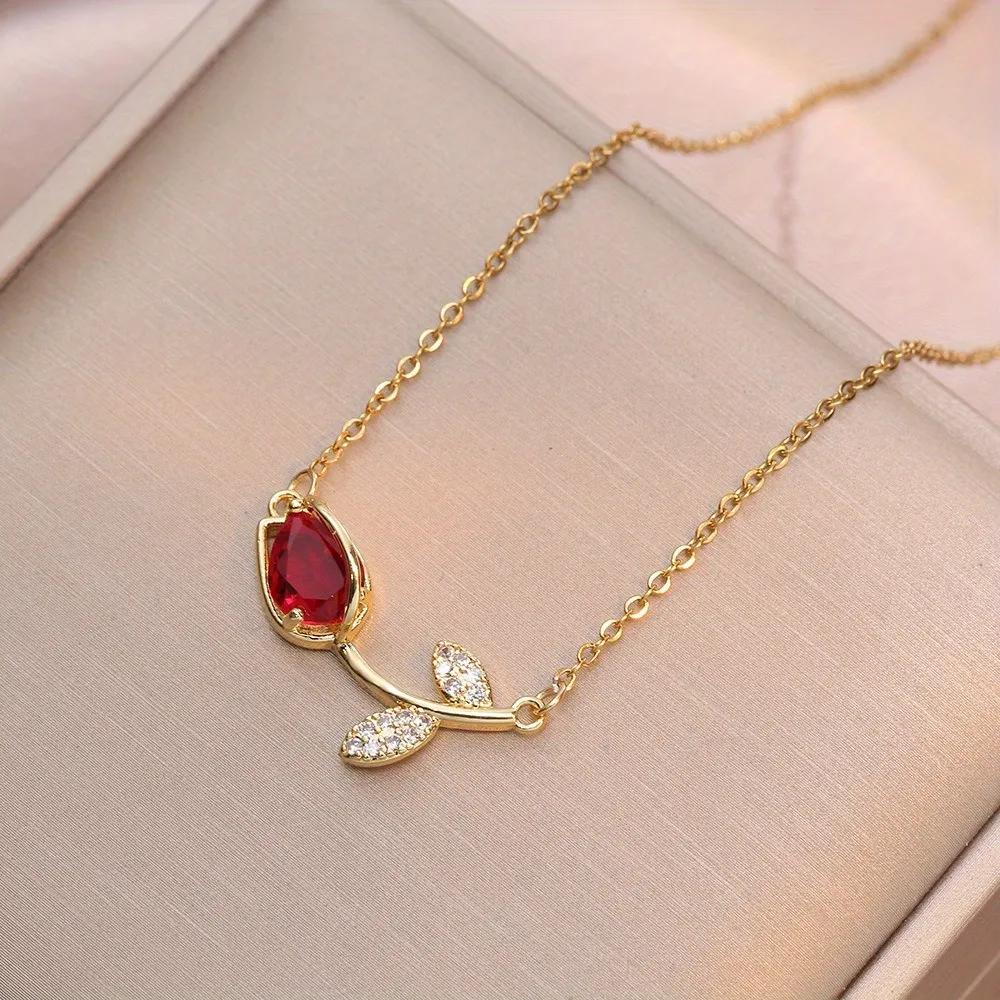 Gold-finished chain necklace with a ruby-red cubic zirconia tulip pendant and small leaf stones