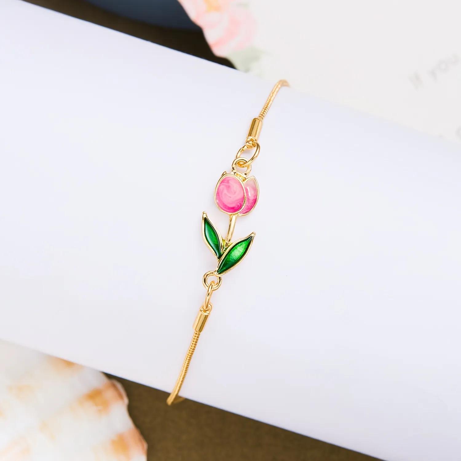 Gold-toned snake chain bracelet with a single bright pink enamel tulip charm and green leaves