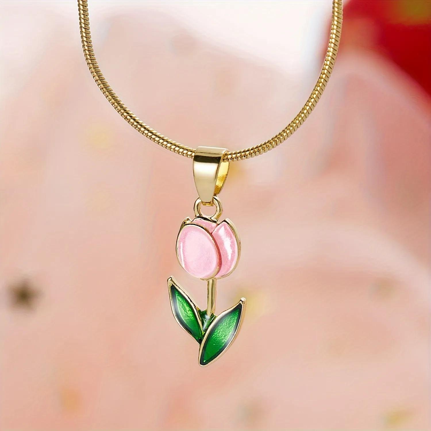 Gold-finished snake chain necklace with a soft blush pink enamel tulip pendant and leaves