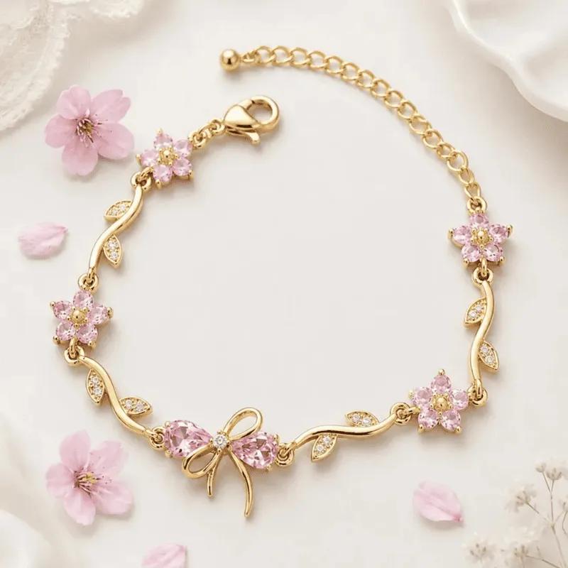 Gold-toned bracelet with pink faceted stone blossoms, pave leaves and a stone-set bow charm