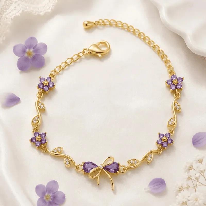 Gold-toned bracelet with purple faceted stone blossoms, pave leaves and a stone-set bow charm