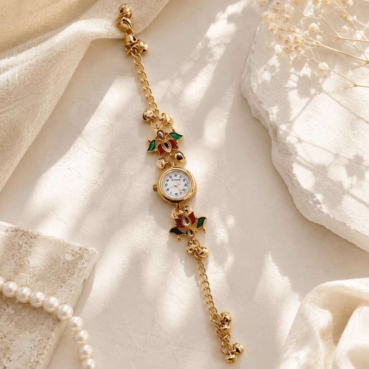 Gold chain bracelet watch with lotus-shaped kundan-style charms and ghungroo bells either side of a white dial