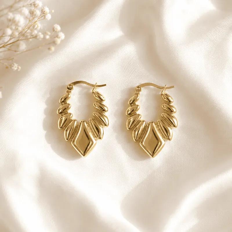 Gold-plated steel hoop earrings with raised oval petal fringe and a diamond-shaped centrepiece