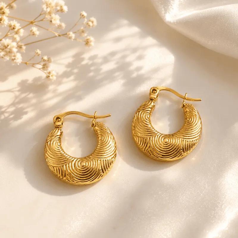 Small gold-plated steel crescent hoop earrings with a tight concentric spiral texture