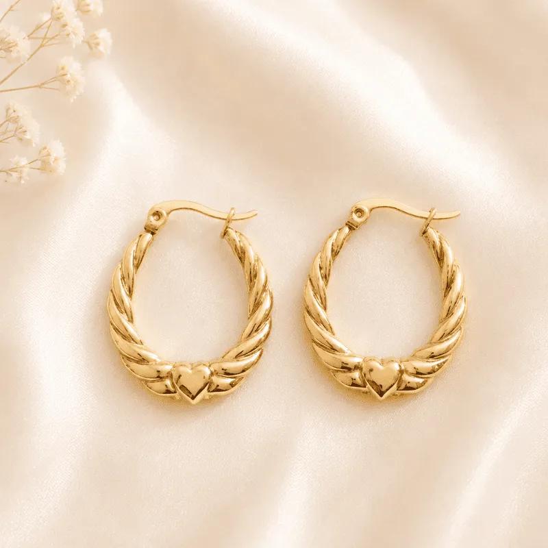 Gold-plated steel oval hoop earrings with a twisted rope texture and a small raised heart charm