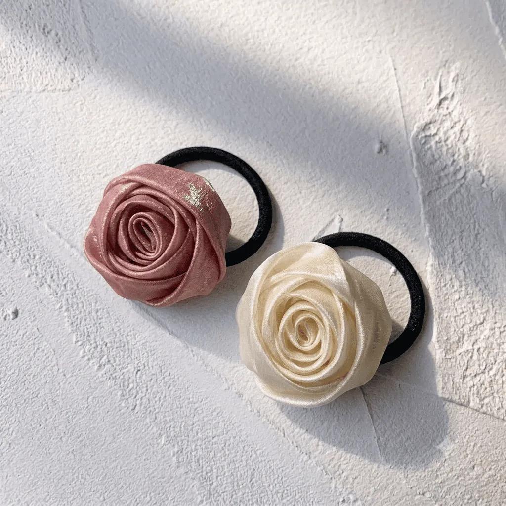 Two satin rosette hair ties in pink and cream on soft stretch elastic bands