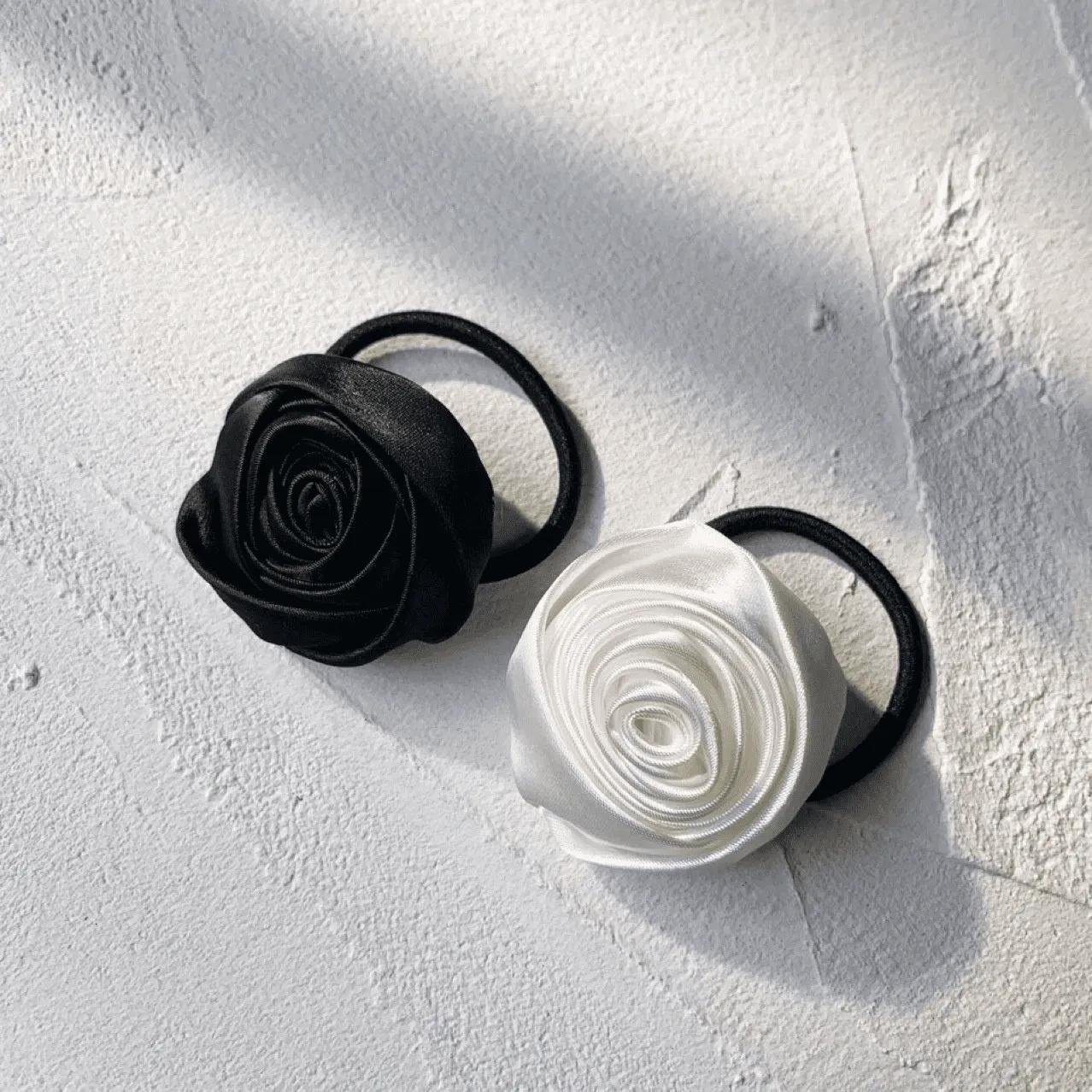 Two satin rosette hair ties in black and white on soft stretch elastic bands
