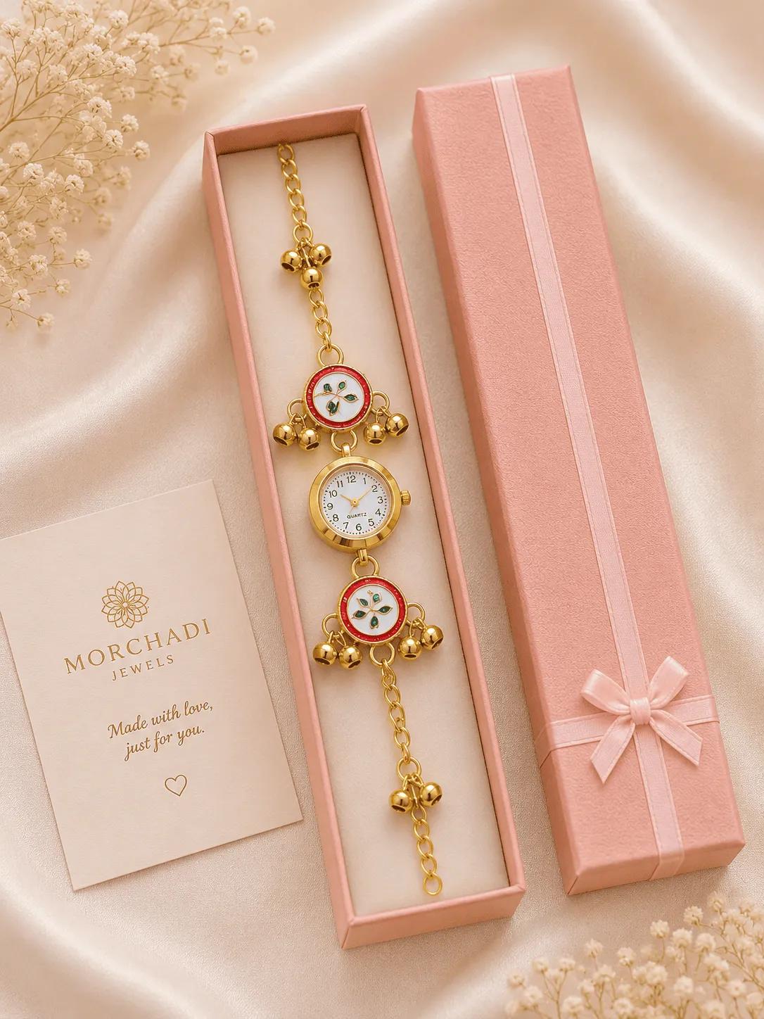 Gold-plated bracelet watch with white dial, red and green floral meenakari roundels and ghungroo bells in a pink gift box