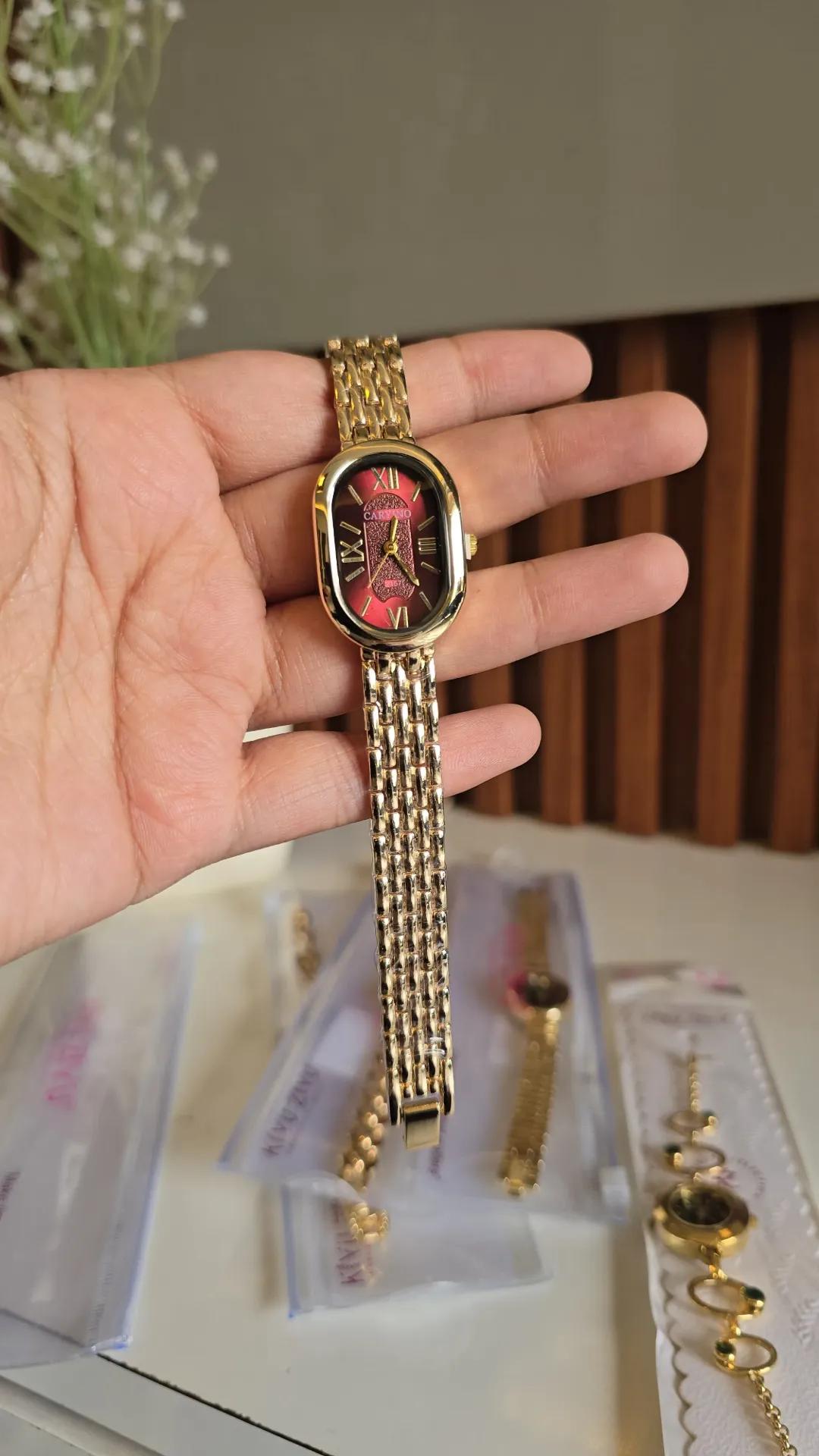 Gold-tone textured bracelet watch with a red oval dial and roman numerals
