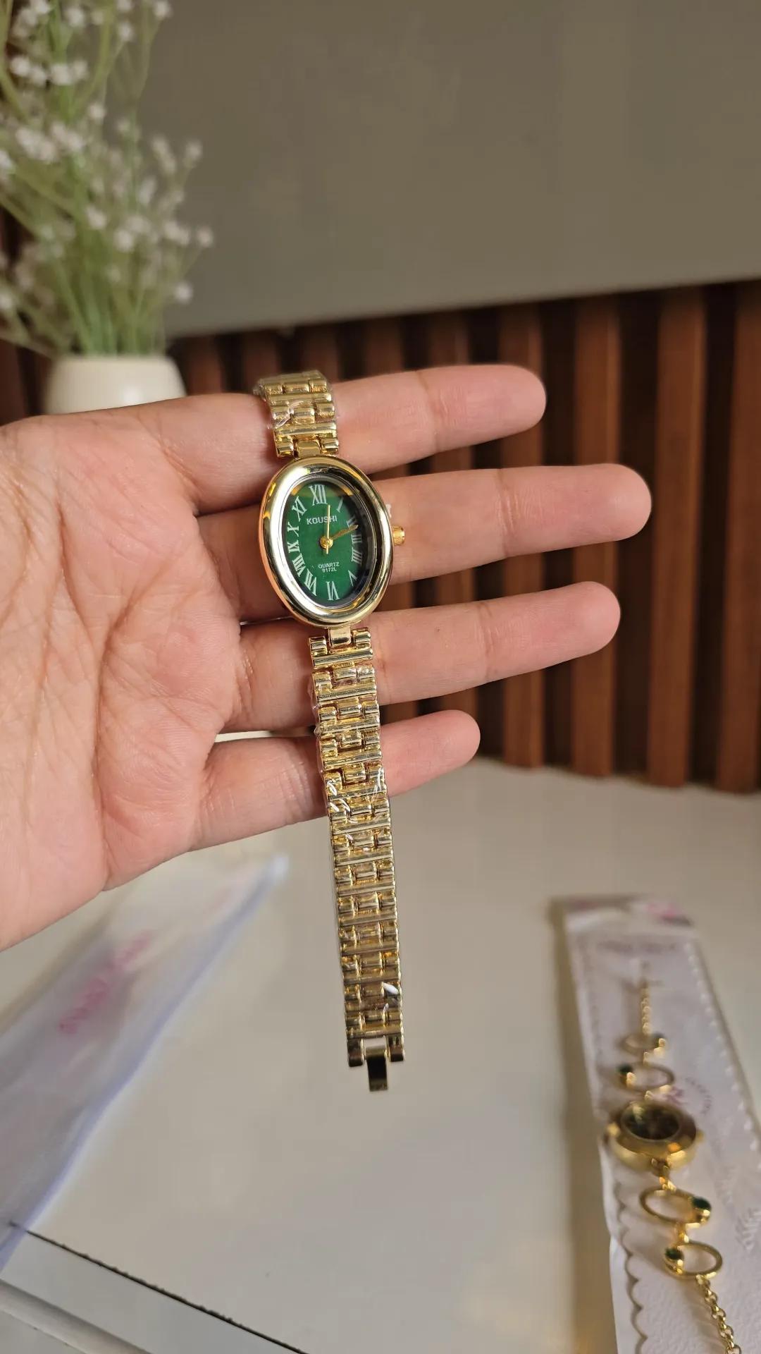 Gold-tone brick-link bracelet watch with a green oval dial and roman numerals