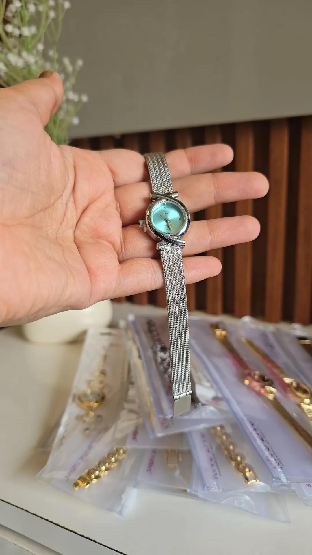 Silver-tone mesh bracelet watch with an aqua blue dial and bow-shaped detailing at the case edge