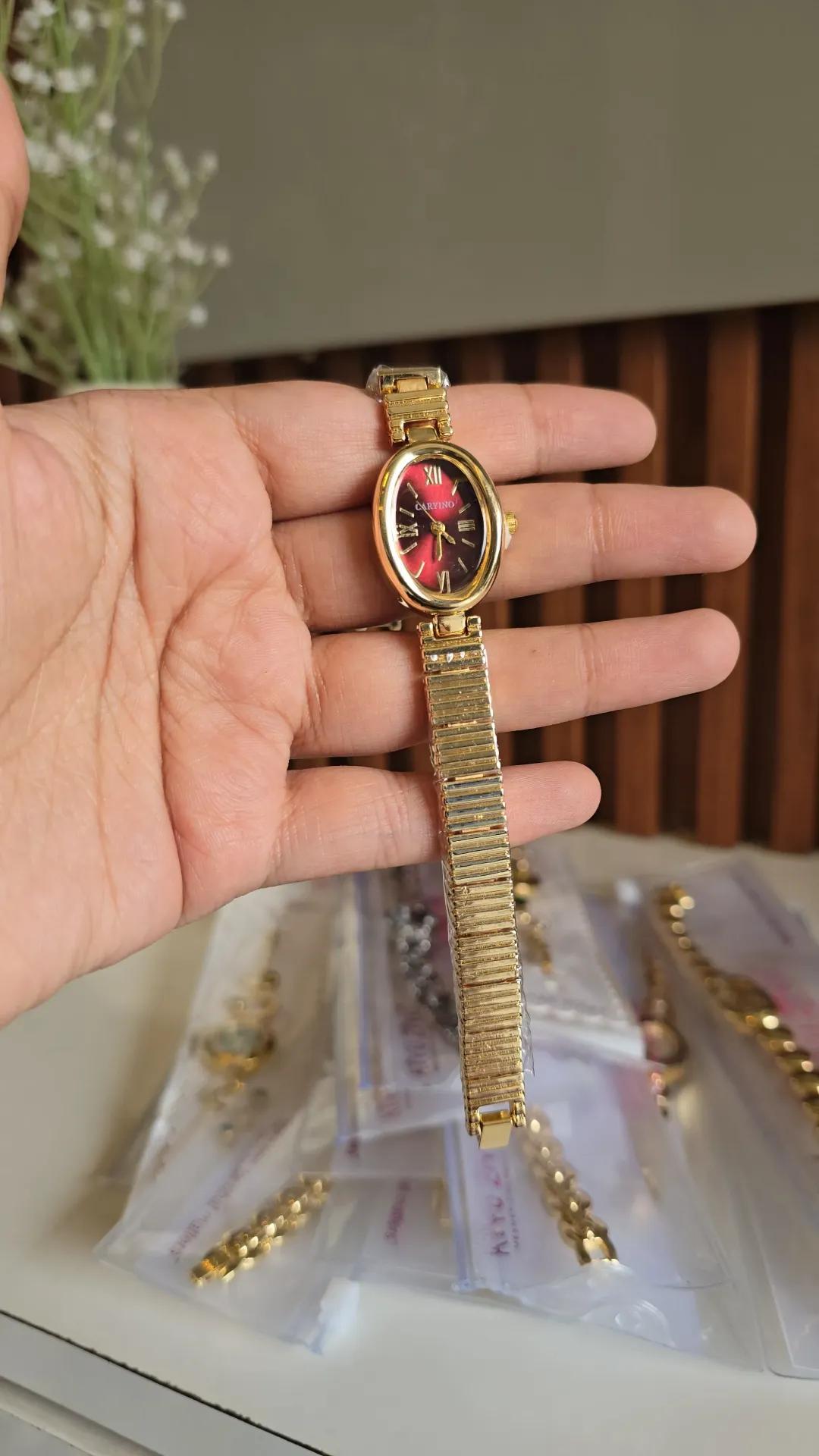 Gold-tone ribbed bracelet watch with a deep red dial and roman numeral markers