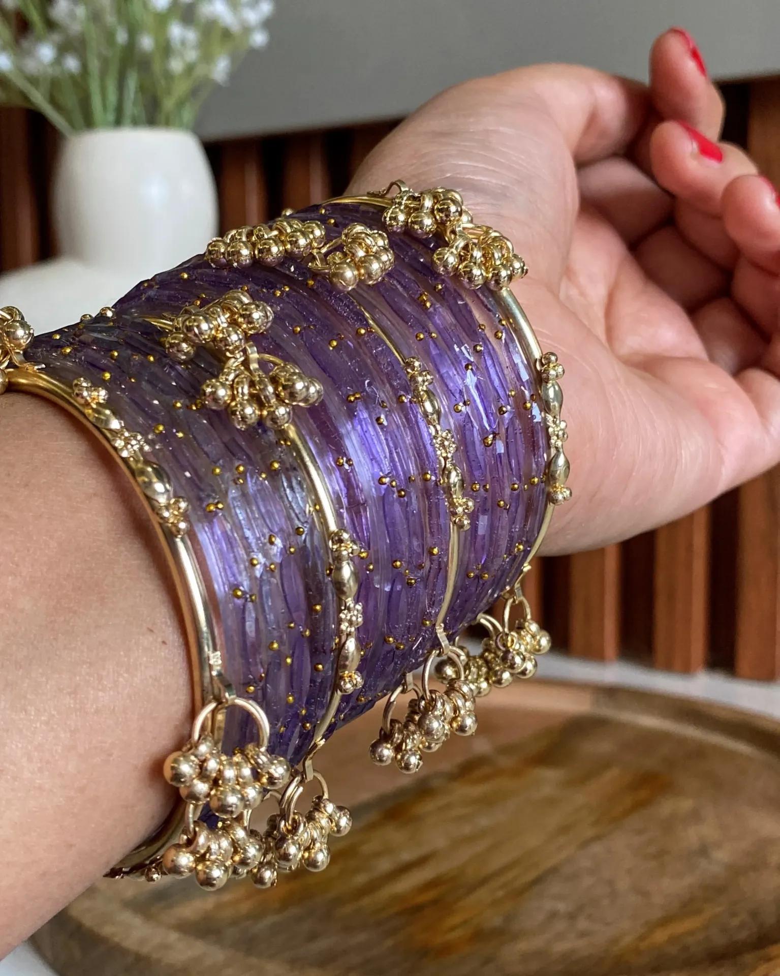 Sixteen deep purple lacquered glass bangles with gold-tone beadwork and hanging bells