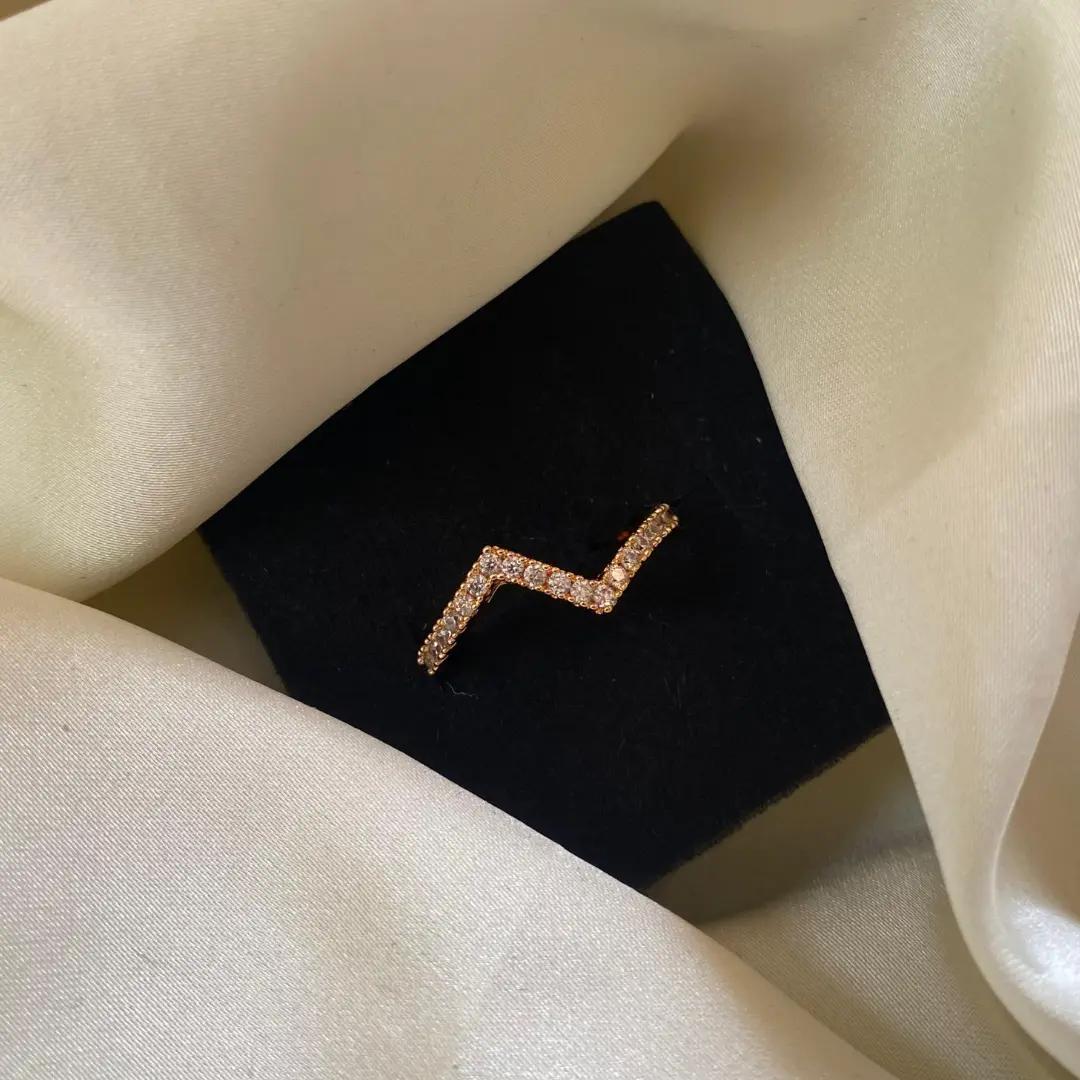 Rosegold-plated ring with a zig-zag band lined in tiny cubic zirconia stones on a black velvet card