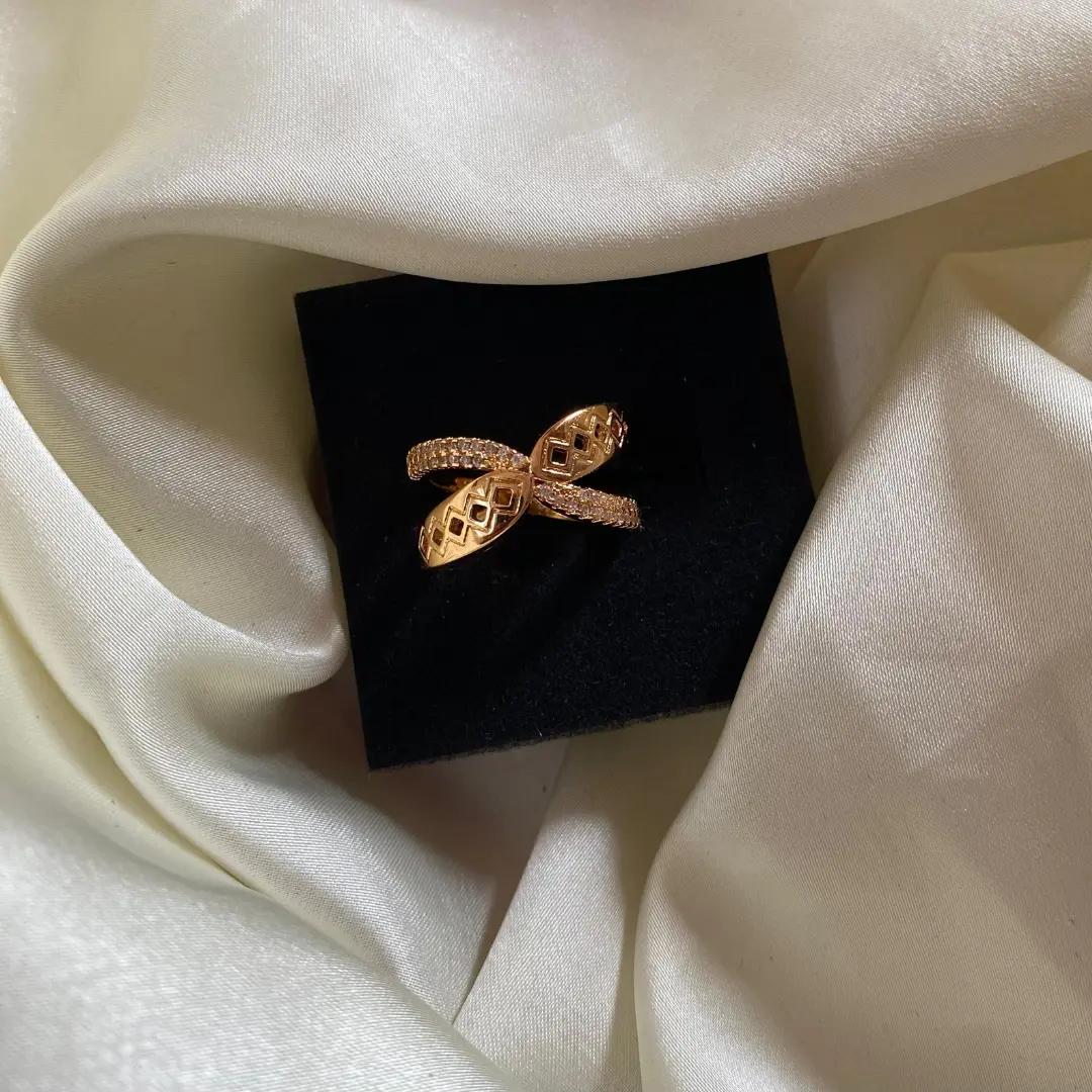 Two crossing rose gold-plated bands, one pavé-set with cubic zirconia and one ending in pierced lattice tips